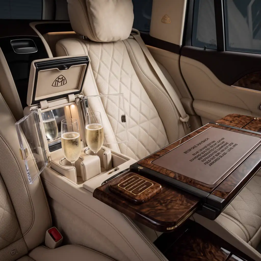 Maybach rear lounge with champagne flutes, walnut desk, and quilted cream leather