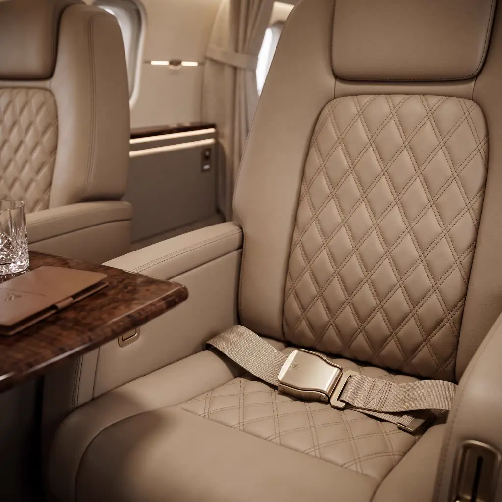 Quilted champagne leather cabin seat with gold buckle and burl side table